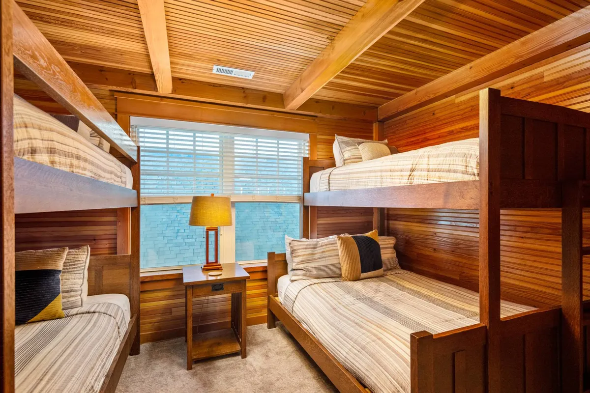 A welcoming bunk room with charming wooden bunk beds, striped bedding, and a soft-glow lamp. The space feels playful yet comfortable, designed with children or younger guests in mind, providing both fun and functionality.