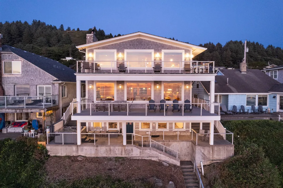 An exterior perspective shows a spacious balcony with large windows and modern architectural design, offering ample room for outdoor dining or evening gatherings. The view hints at the ocean beyond, suggesting seamless indoor-outdoor living and the deck's role as a communal gathering space.