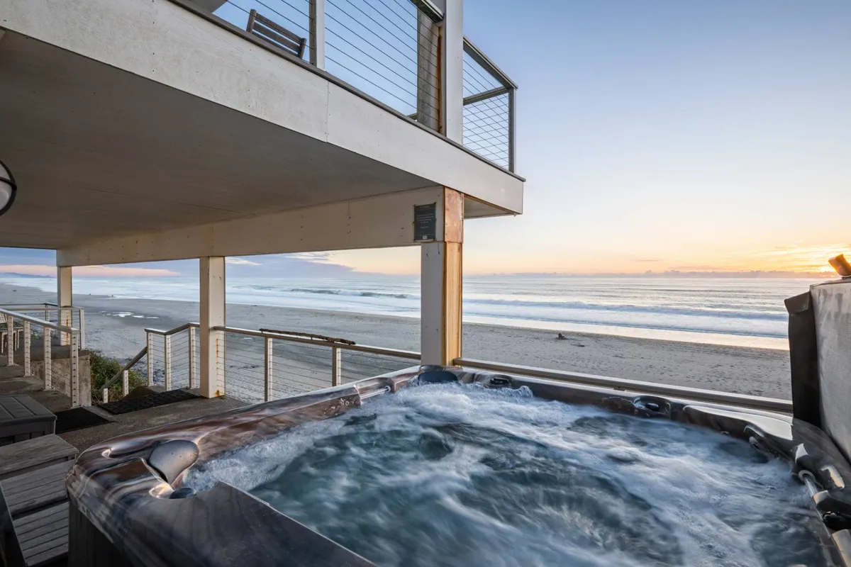 This image features a tranquil hot tub on a deck, overlooking the ocean. The scene exudes relaxation, with the bubbling water of the hot tub inviting guests to unwind while enjoying panoramic ocean views and fresh sea breezes. The deck area provides an outdoor sanctuary, perfect for socializing or soaking under the open sky.